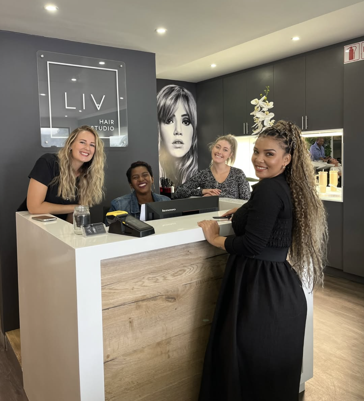 The Liv Hair Studio team at the reception desk beneath the LIV Hair Studio sign
